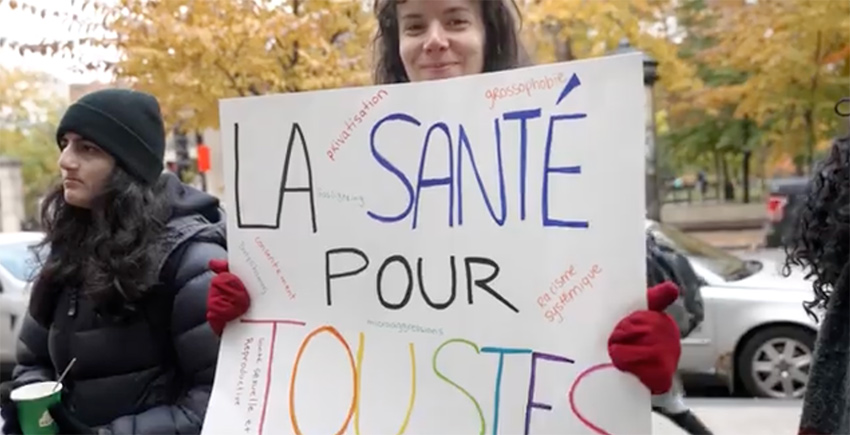 Participante à l'action d’éclat pour l’accès des femmes aux soins de santé tenant une pancarte La santé pour toutes